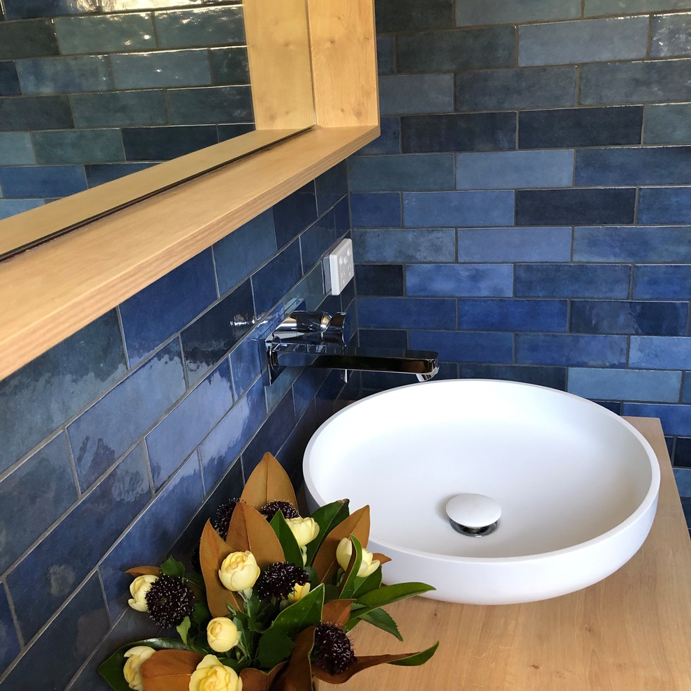 Источник вдохновения для домашнего уюта: главная ванная комната среднего размера в современном стиле с плоскими фасадами, светлыми деревянными фасадами, открытым душем, раздельным унитазом, синей плиткой, керамической плиткой, синими стенами, полом из керамической плитки, настольной раковиной, столешницей из дерева, серым полом, открытым душем и бежевой столешницей