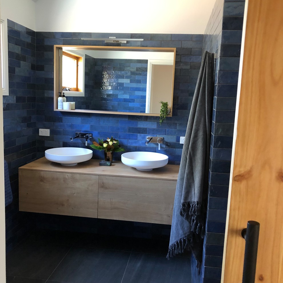 他の地域にあるお手頃価格の中くらいなコンテンポラリースタイルのおしゃれなマスターバスルーム (フラットパネル扉のキャビネット、淡色木目調キャビネット、オープン型シャワー、分離型トイレ、青いタイル、セラミックタイル、青い壁、セラミックタイルの床、ベッセル式洗面器、木製洗面台、グレーの床、オープンシャワー、ベージュのカウンター) の写真