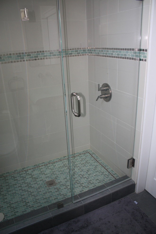 На фото: ванная комната в современном стиле с душем в нише, белой плиткой, керамогранитной плиткой, белыми стенами, монолитной раковиной, стеклянной столешницей и душем с распашными дверями