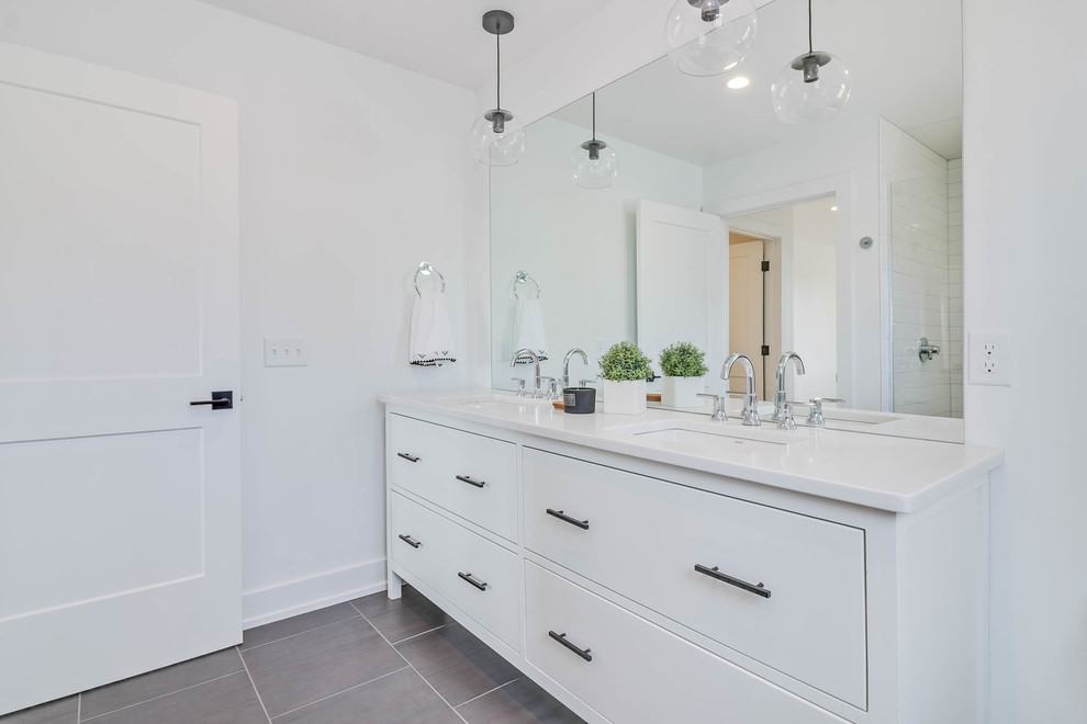 Inspiration for a mid-sized cottage master white tile and subway tile porcelain tile and gray floor corner shower remodel in Grand Rapids with flat-panel cabinets, white cabinets, white walls, an undermount sink, solid surface countertops and a hinged shower door