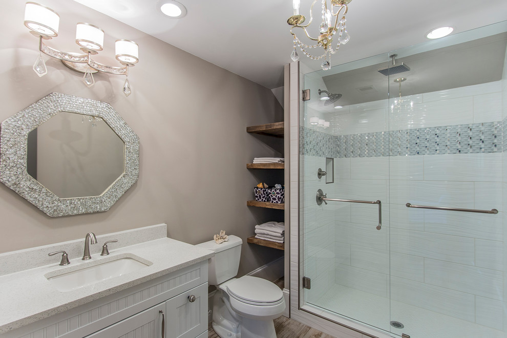 Design ideas for a medium sized classic shower room bathroom in Other with beaded cabinets, white cabinets, a walk-in shower, a two-piece toilet, white tiles, metro tiles, grey walls, ceramic flooring, a built-in sink, quartz worktops, grey floors and a hinged door.