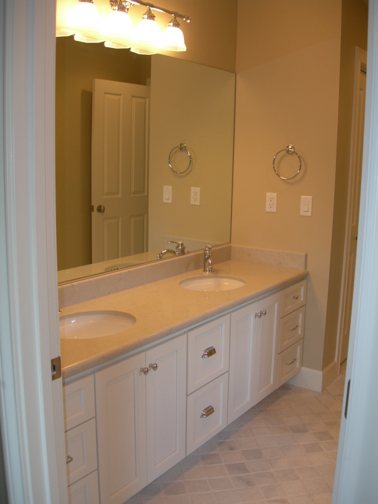 Klassisk inredning av ett mellanstort badrum för barn, med ett undermonterad handfat, möbel-liknande, vita skåp, bänkskiva i kvarts, ett badkar i en alkov, en dusch/badkar-kombination, en toalettstol med separat cisternkåpa, vit kakel, grå väggar och marmorgolv
