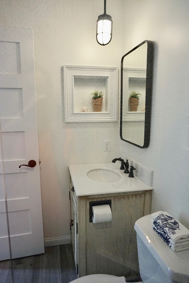 This is an example of a small beach style shower room bathroom in Charleston with louvered cabinets, beige cabinets, an alcove shower, a two-piece toilet, blue tiles, ceramic tiles, white walls, porcelain flooring, a submerged sink, engineered stone worktops, brown floors, a hinged door and white worktops.