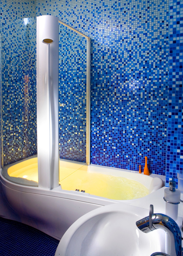 Ejemplo de cuarto de baño infantil contemporáneo de tamaño medio con armarios tipo mueble, puertas de armario blancas, bañera empotrada, combinación de ducha y bañera, sanitario de pared, baldosas y/o azulejos azules, baldosas y/o azulejos en mosaico, paredes azules, suelo con mosaicos de baldosas y lavabo integrado