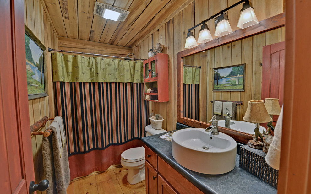 Modelo de cuarto de baño clásico con lavabo sobreencimera, armarios con paneles lisos, puertas de armario de madera oscura y combinación de ducha y bañera