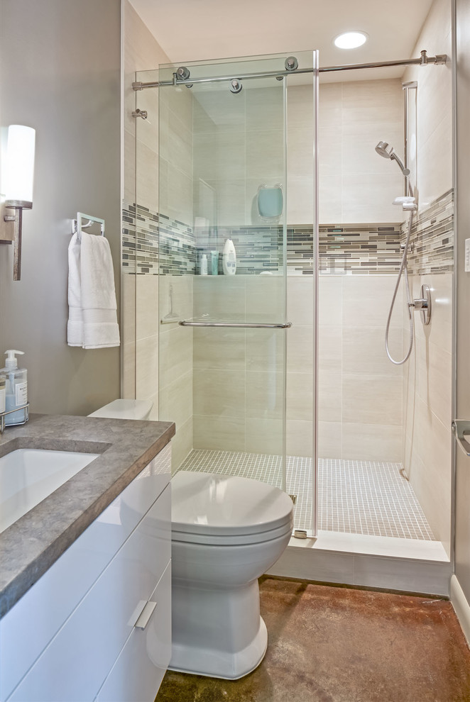 Example of a large trendy 3/4 white tile and ceramic tile concrete floor alcove shower design in Seattle with an undermount sink, flat-panel cabinets, white cabinets, limestone countertops, a two-piece toilet and gray walls