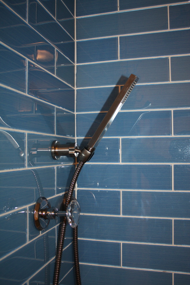 Inredning av ett modernt mellanstort vit vitt badrum med dusch, med öppna hyllor, blå skåp, en dusch i en alkov, blå kakel, tunnelbanekakel, vita väggar, ett fristående handfat, bänkskiva i akrylsten och grått golv