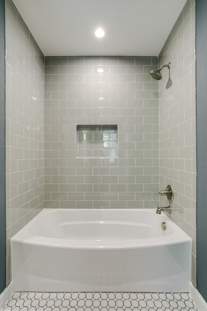 Cette image montre une salle de bain traditionnelle de taille moyenne avec un placard à porte shaker, des portes de placard blanches, une baignoire en alcôve, un combiné douche/baignoire, WC séparés, des carreaux de céramique, un mur gris, un sol en carrelage de céramique, un lavabo encastré, un plan de toilette en quartz modifié et un carrelage gris.