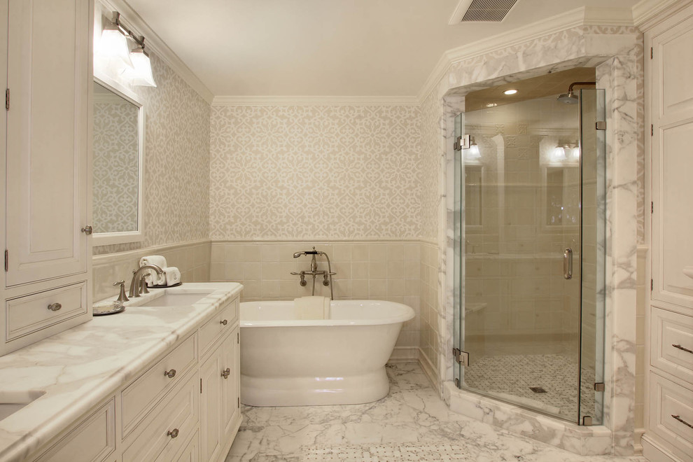 На фото: большая ванная комната в классическом стиле с врезной раковиной, фасадами с декоративным кантом, белыми фасадами, мраморной столешницей, отдельно стоящей ванной, угловым душем, белой плиткой, каменной плиткой и мраморным полом