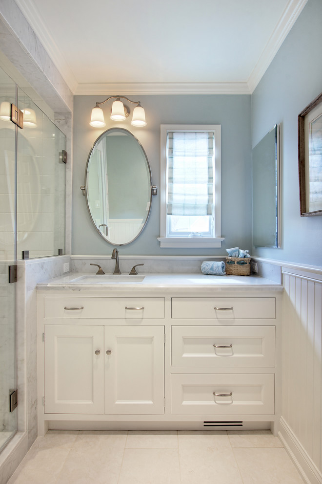 This is an example of a medium sized classic bathroom in Philadelphia with a built-in sink, recessed-panel cabinets, white cabinets, marble worktops, an alcove shower, white tiles, stone tiles, blue walls and marble flooring.