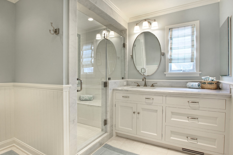 Inspiration for a mid-sized transitional white tile and stone tile marble floor alcove shower remodel in Philadelphia with a drop-in sink, recessed-panel cabinets, white cabinets, marble countertops and blue walls