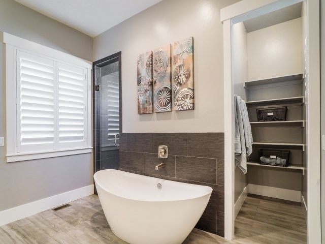 Mid-sized transitional master light wood floor freestanding bathtub photo in Salt Lake City with an undermount sink, shaker cabinets, dark wood cabinets, quartzite countertops, a two-piece toilet and gray walls