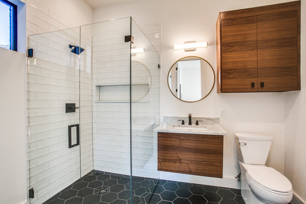 Inspiration for a mid-sized modern 3/4 white tile and ceramic tile porcelain tile and black floor bathroom remodel in Dallas with flat-panel cabinets, medium tone wood cabinets, a one-piece toilet, white walls, an undermount sink, marble countertops and a hinged shower door