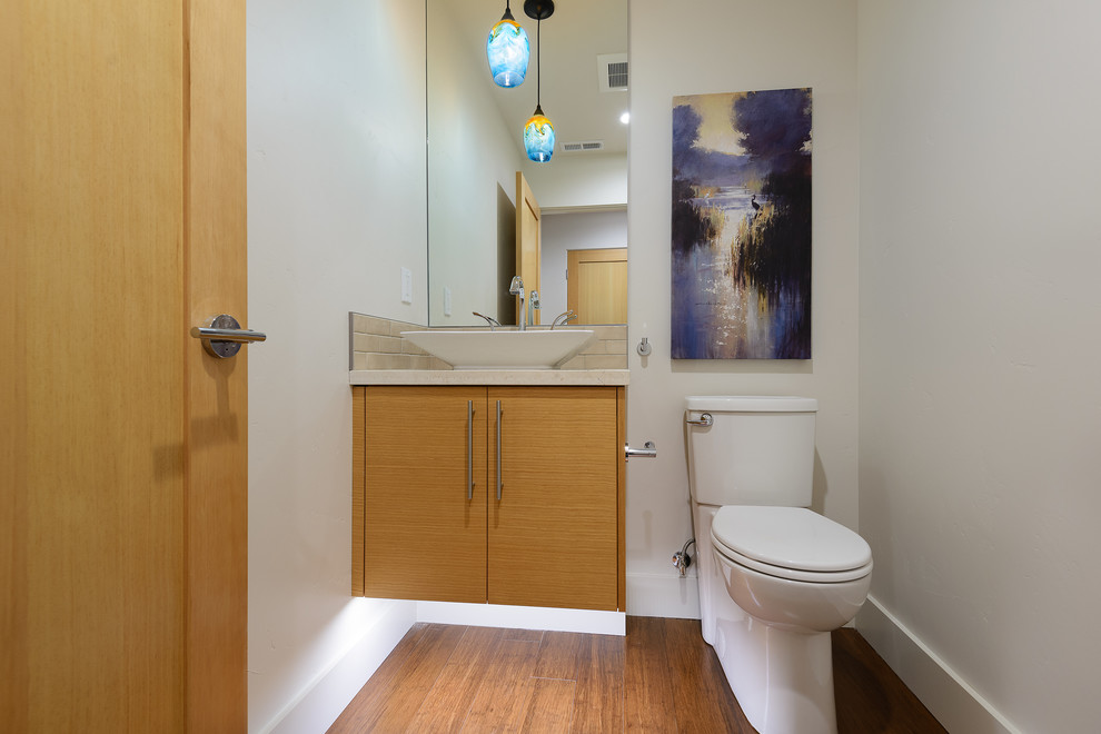 На фото: маленькая главная ванная комната в современном стиле с плоскими фасадами, фасадами цвета дерева среднего тона, унитазом-моноблоком, полом из бамбука, настольной раковиной и столешницей из известняка для на участке и в саду с