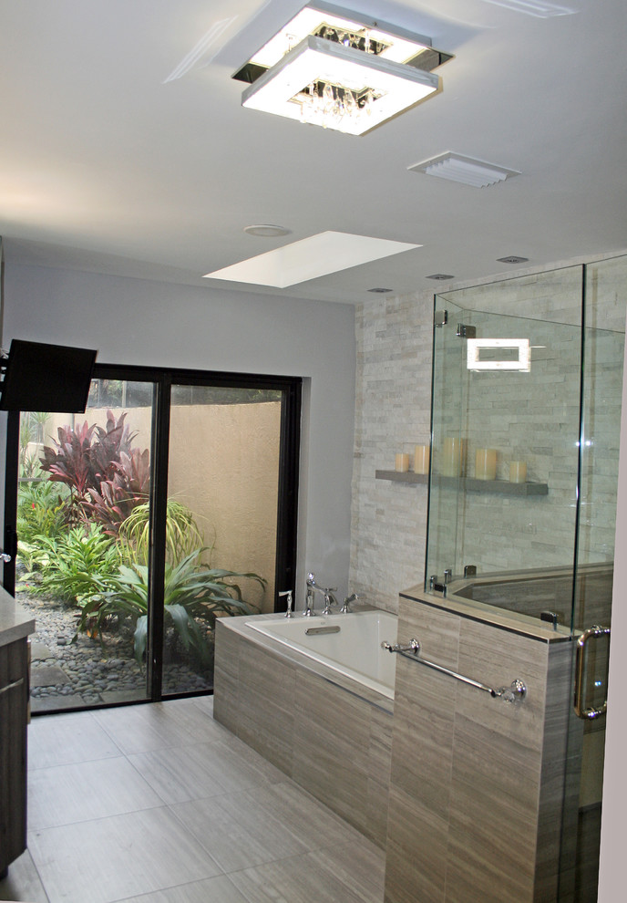 Large modern ensuite bathroom in Miami with flat-panel cabinets, grey cabinets, a built-in bath, grey tiles, porcelain flooring, an alcove shower, a one-piece toilet, stone tiles, beige walls, a submerged sink, terrazzo worktops, grey floors and a hinged door.