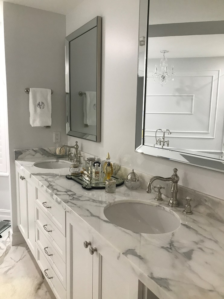 Пример оригинального дизайна: большая главная ванная комната в стиле неоклассика (современная классика) с фасадами с утопленной филенкой, белыми фасадами, отдельно стоящей ванной, угловым душем, серой плиткой, белой плиткой, мраморной плиткой, серыми стенами, мраморным полом, врезной раковиной, мраморной столешницей, серым полом, душем с распашными дверями и серой столешницей