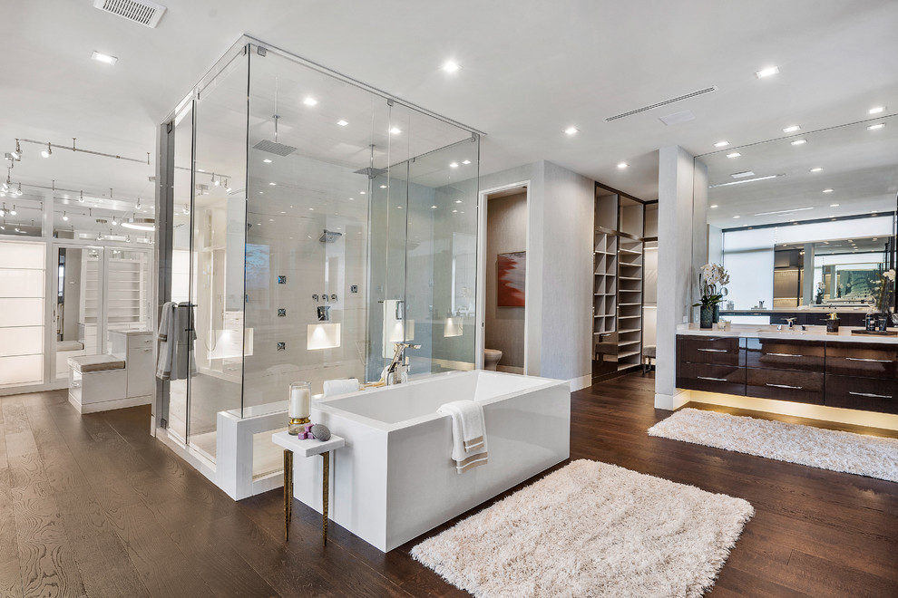 Exempel på ett stort modernt vit vitt en-suite badrum, med släta luckor, skåp i mörkt trä, ett fristående badkar, en dubbeldusch, en vägghängd toalettstol, beige väggar, mellanmörkt trägolv, ett integrerad handfat, bänkskiva i onyx, brunt golv och dusch med gångjärnsdörr