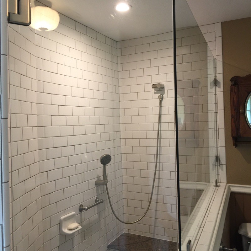 Medium sized traditional ensuite bathroom in Austin with a submerged sink, shaker cabinets, white cabinets, engineered stone worktops, a corner shower, a two-piece toilet, white tiles, ceramic tiles and brown walls.