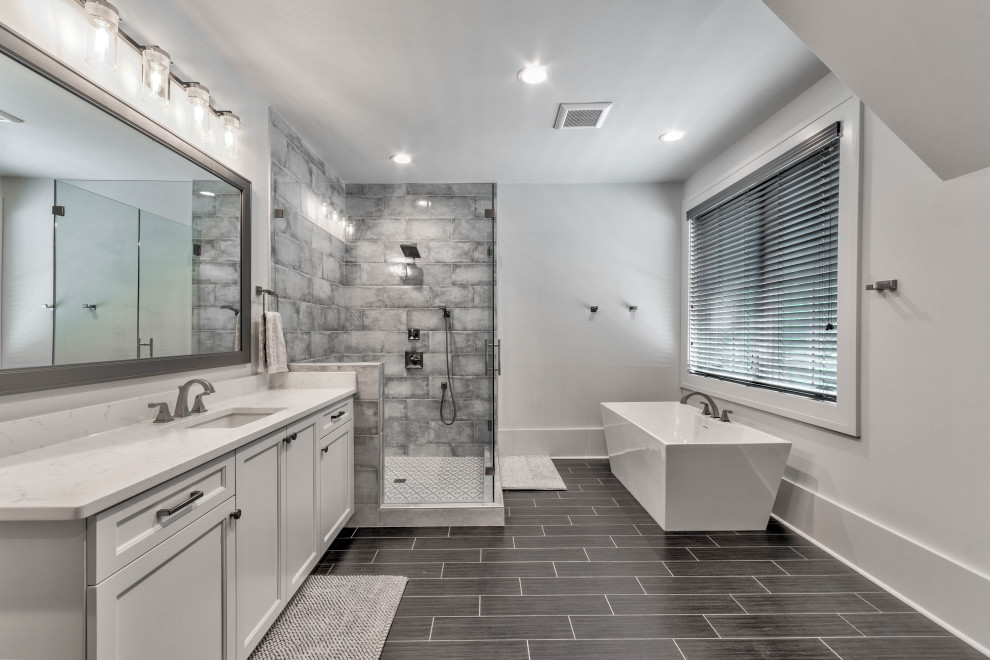 Inspiration for a large modern family bathroom in Atlanta with shaker cabinets, white cabinets, a freestanding bath, grey tiles, porcelain tiles, white walls, porcelain flooring, a submerged sink, engineered stone worktops, black floors, a hinged door, white worktops, a shower bench, a single sink and a built in vanity unit.