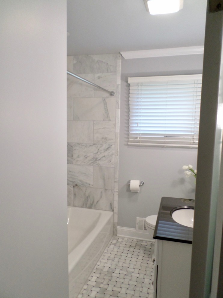 Bild på ett mellanstort funkis en-suite badrum, med luckor med upphöjd panel, vita skåp, ett badkar i en alkov, en dusch/badkar-kombination, en toalettstol med separat cisternkåpa, vit kakel, marmorkakel, grå väggar, marmorgolv, ett undermonterad handfat, vitt golv och dusch med duschdraperi