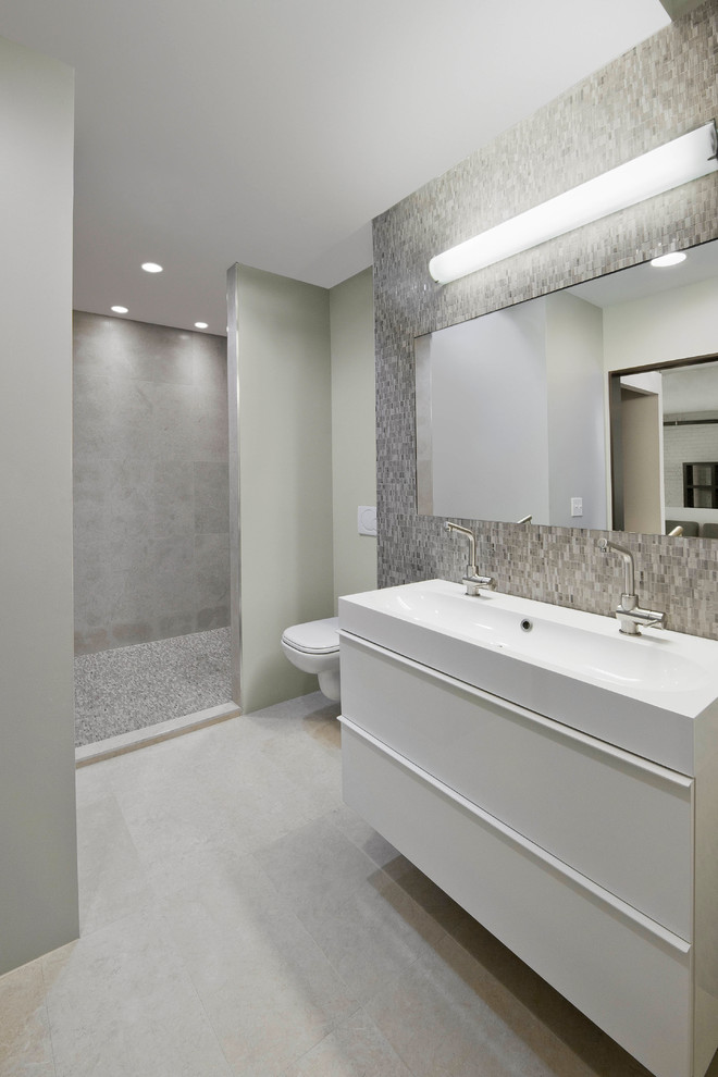 Inspiration for a mid-sized modern master gray tile and ceramic tile ceramic tile doorless shower remodel in Boston with an integrated sink, flat-panel cabinets, white cabinets, solid surface countertops, a one-piece toilet and white walls