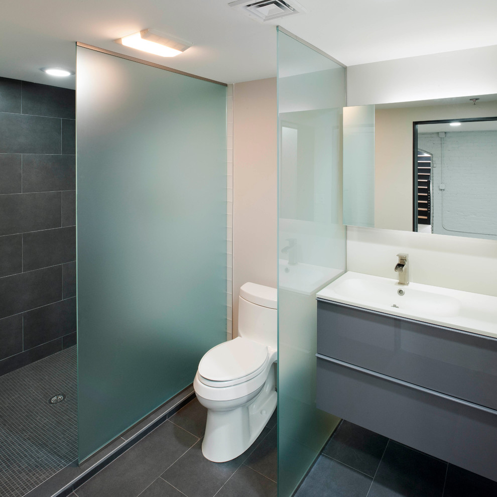 Example of a mid-sized minimalist master gray tile and ceramic tile ceramic tile doorless shower design in Boston with an integrated sink, flat-panel cabinets, gray cabinets, solid surface countertops, a one-piece toilet and white walls
