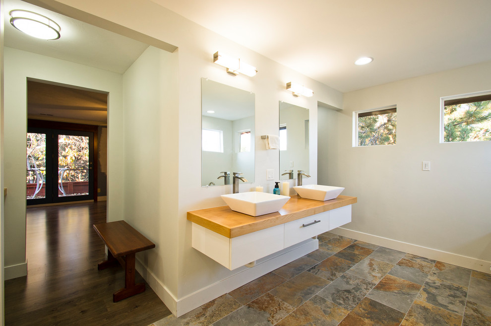 На фото: большая главная ванная комната в скандинавском стиле с открытыми фасадами, накладной ванной, унитазом-моноблоком, полом из керамогранита и столешницей из дерева с