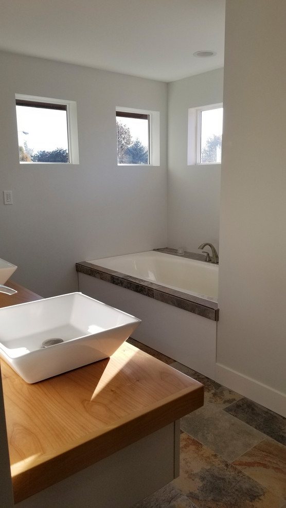 На фото: большая главная ванная комната в скандинавском стиле с открытыми фасадами, накладной ванной, унитазом-моноблоком, полом из керамогранита и столешницей из дерева
