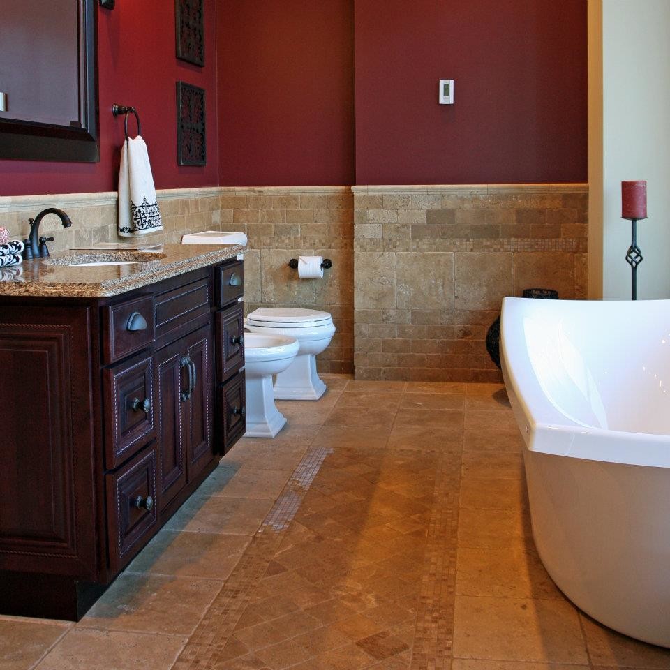 Foto på ett mellanstort medelhavsstil en-suite badrum, med ett undermonterad handfat, luckor med upphöjd panel, skåp i mörkt trä, bänkskiva i kvarts, ett fristående badkar, en bidé, beige kakel, stenkakel, röda väggar och travertin golv