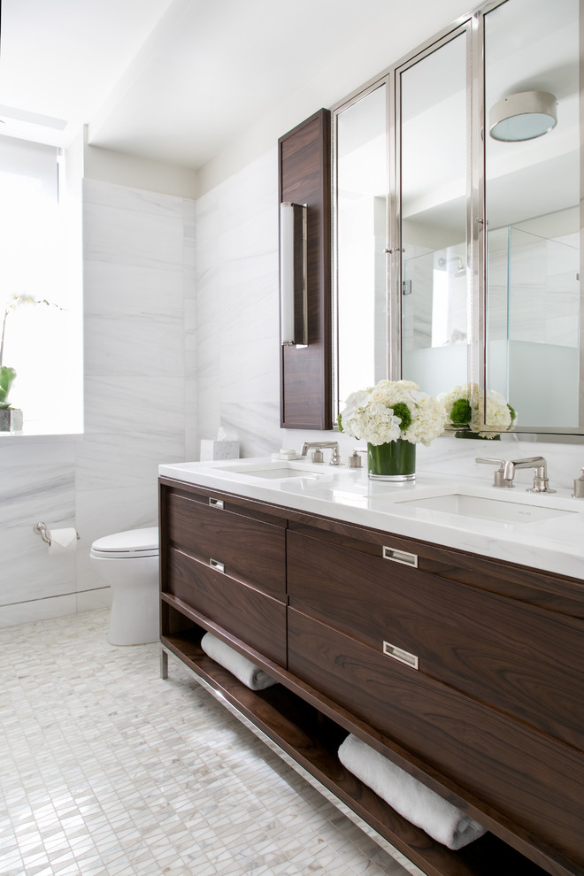 Photo of a large contemporary shower room bathroom in DC Metro with a one-piece toilet, white tiles, a submerged sink, brown cabinets, a corner shower, marble tiles, white walls, white floors, solid surface worktops, white worktops and flat-panel cabinets.
