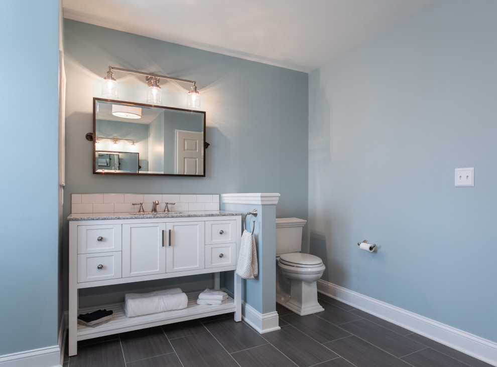 Пример оригинального дизайна: большая главная ванная комната в стиле неоклассика (современная классика) с фасадами в стиле шейкер, белыми фасадами, угловым душем, унитазом-моноблоком, белой плиткой, керамической плиткой, синими стенами, полом из керамической плитки, врезной раковиной, столешницей из гранита, серым полом, душем с распашными дверями, серой столешницей, нишей, тумбой под одну раковину и напольной тумбой