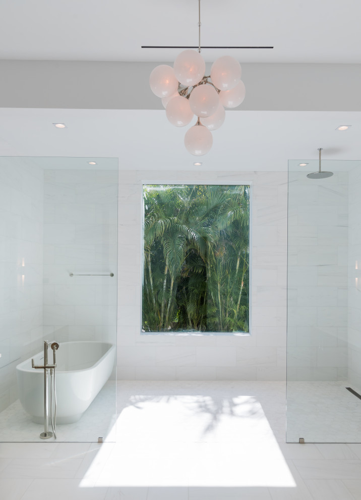 Inredning av ett modernt badrum, med ett fristående badkar, en kantlös dusch, vit kakel, vitt golv och med dusch som är öppen