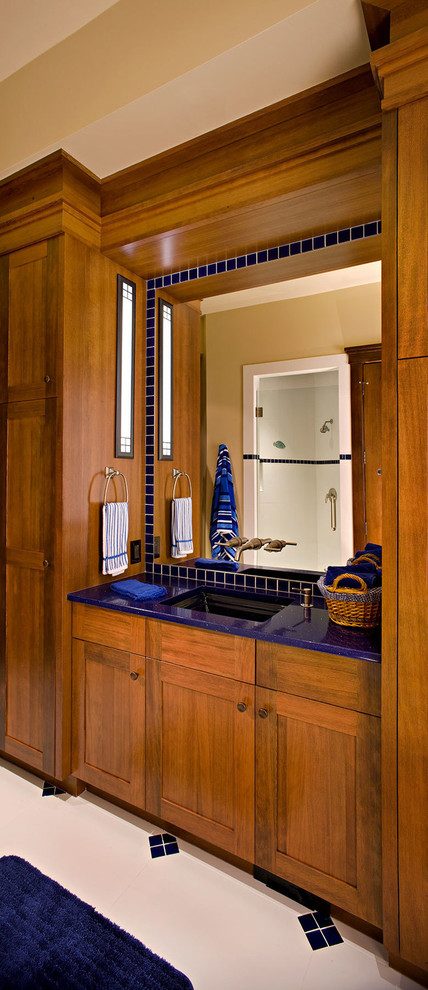 Идея дизайна: огромная ванная комната в стиле ретро с накладной раковиной, плоскими фасадами, фасадами цвета дерева среднего тона, стеклянной столешницей, синей плиткой, стеклянной плиткой, бежевыми стенами, полом из керамической плитки и душевой кабиной
