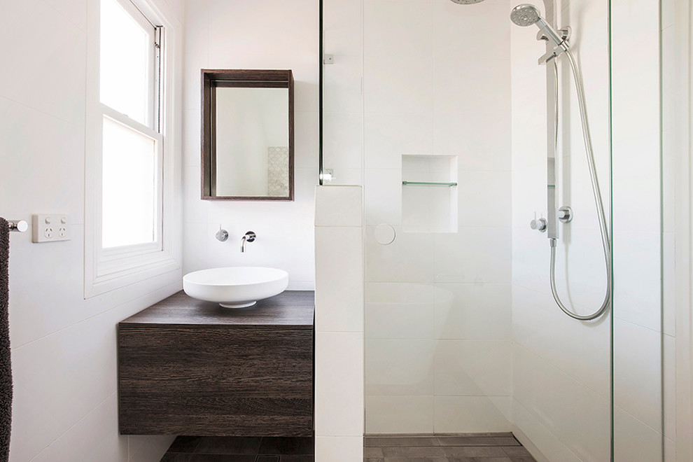 Пример оригинального дизайна: ванная комната в современном стиле с плоскими фасадами, темными деревянными фасадами, угловым душем, белой плиткой, белыми стенами, настольной раковиной, столешницей из дерева, серым полом, душем с распашными дверями и коричневой столешницей
