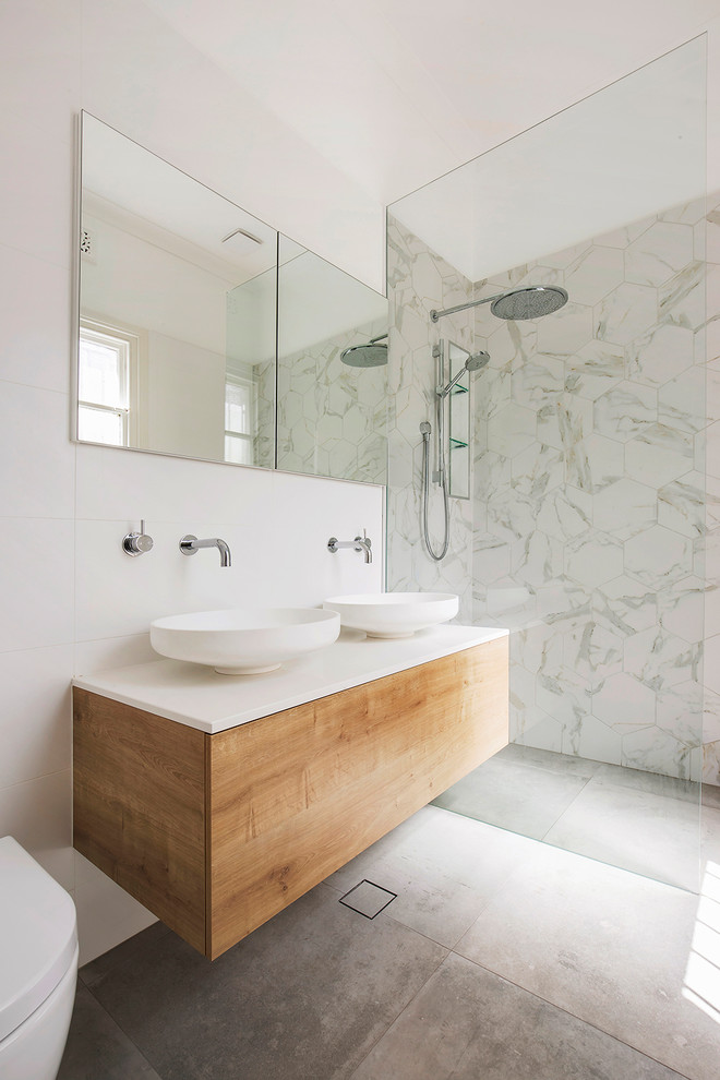 Design ideas for a contemporary bathroom in Sydney with flat-panel cabinets, medium wood cabinets, a built-in shower, a wall mounted toilet, white tiles, white walls, a vessel sink, grey floors, an open shower and white worktops.