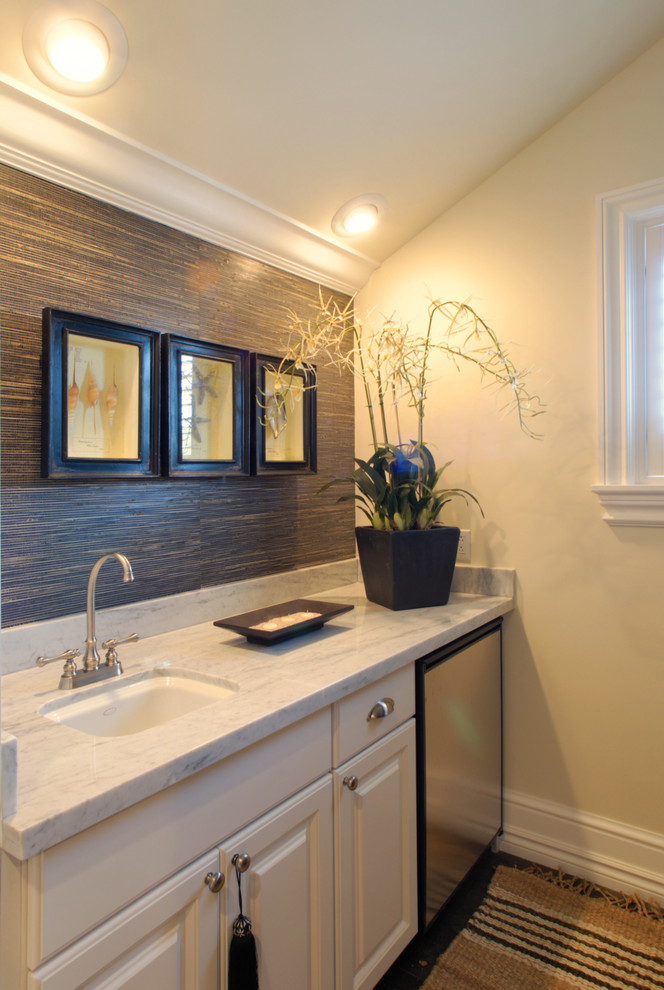 Foto di una stanza da bagno tropicale con lavabo sottopiano, ante con bugna sagomata e ante beige