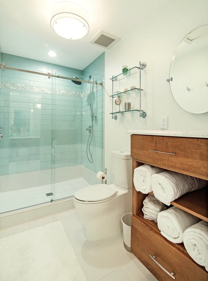 Modern inredning av ett badrum, med ett undermonterad handfat, skåp i mellenmörkt trä, bänkskiva i kvarts, en dusch i en alkov, en toalettstol med separat cisternkåpa, grön kakel, glaskakel, gröna väggar, klinkergolv i porslin och släta luckor