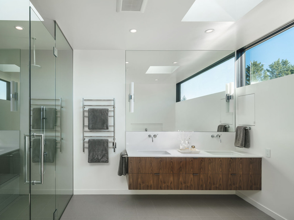 Diseño de cuarto de baño minimalista con armarios con paneles lisos, puertas de armario de madera en tonos medios, paredes blancas, lavabo bajoencimera, suelo gris y encimeras blancas