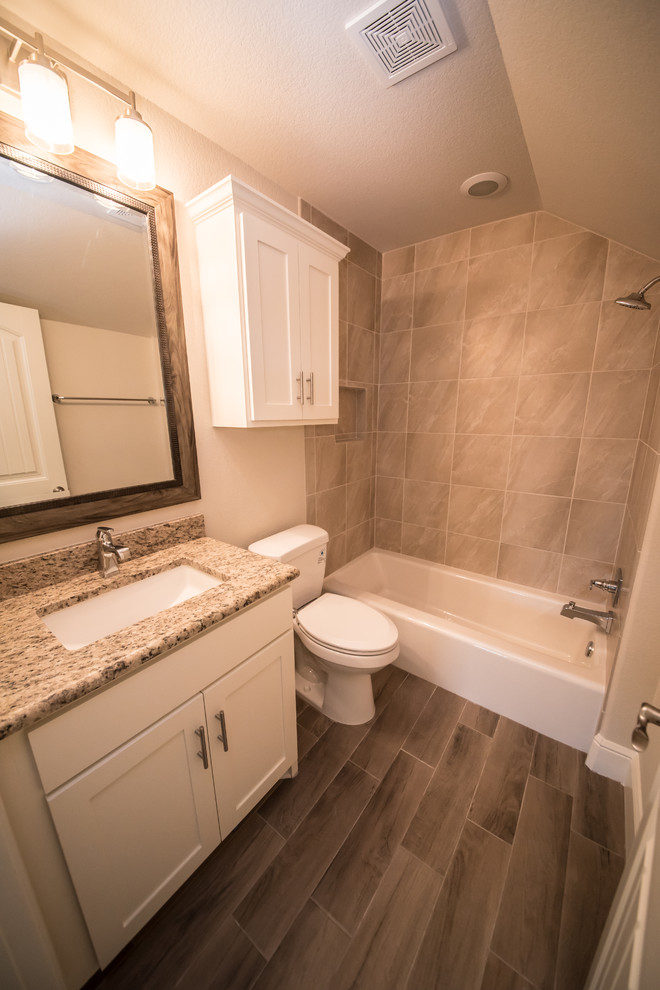 Tub/shower combo - mid-sized craftsman 3/4 beige tile and ceramic tile ceramic tile tub/shower combo idea in Austin with white cabinets, brown walls, an undermount sink, granite countertops, shaker cabinets and a two-piece toilet