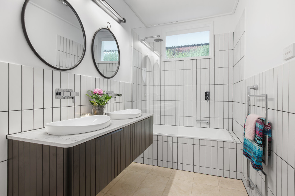 Cette image montre une salle de bain design de taille moyenne avec des portes de placard noires, un combiné douche/baignoire, un carrelage blanc, un mur blanc, un lavabo posé, meuble double vasque et meuble-lavabo suspendu.