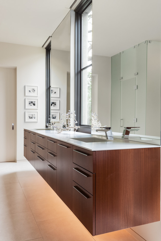 Imagen de cuarto de baño actual con lavabo bajoencimera, armarios con paneles lisos, puertas de armario de madera oscura y baldosas y/o azulejos beige