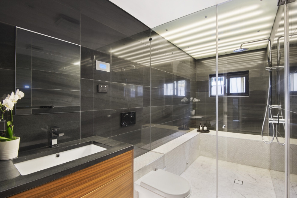 Foto di una stanza da bagno minimal di medie dimensioni con ante lisce, ante in legno scuro, piastrelle nere, top in granito e top nero
