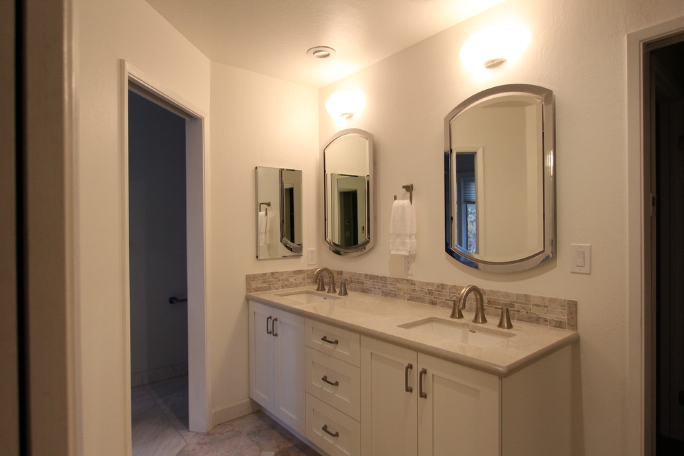 Photo of a medium sized classic ensuite bathroom in San Francisco with a submerged sink, shaker cabinets, white cabinets, engineered stone worktops, marble flooring, a submerged bath, a double shower, a one-piece toilet, beige tiles, stone tiles and white walls.