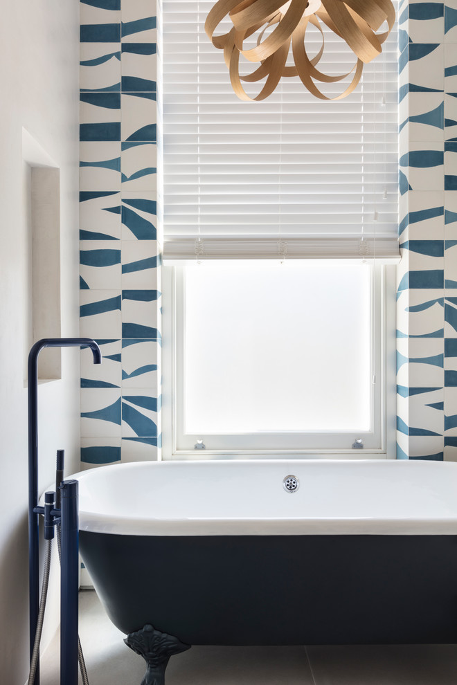 Modelo de cuarto de baño azulejo de dos tonos actual con bañera exenta, baldosas y/o azulejos azules y baldosas y/o azulejos blancos