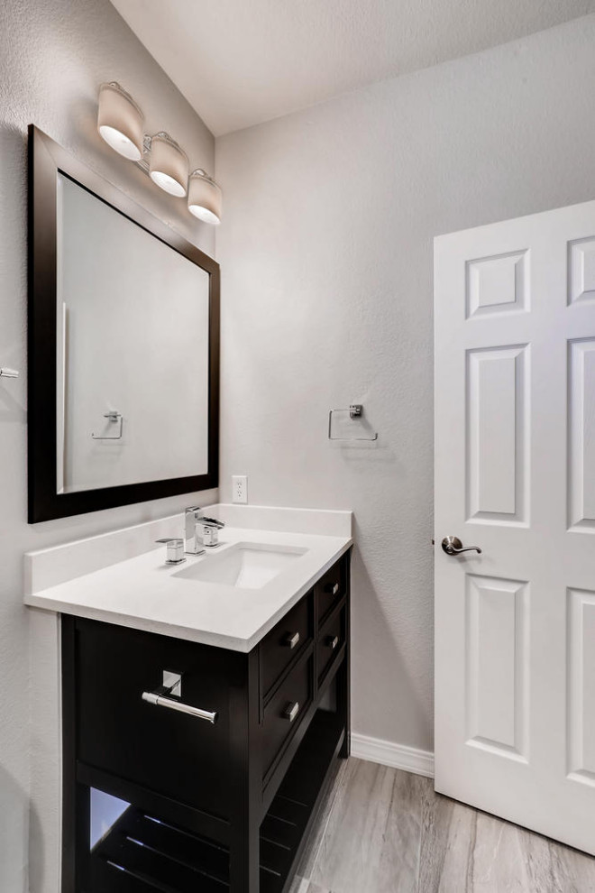 Inspiration for a small contemporary 3/4 gray tile and porcelain tile porcelain tile and single-sink bathroom remodel in Denver with recessed-panel cabinets, black cabinets, a two-piece toilet, gray walls, an undermount sink, quartz countertops, a hinged shower door, white countertops, a niche and a freestanding vanity