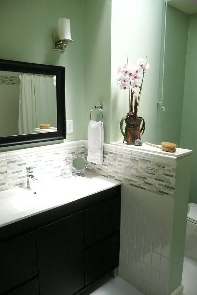 Tub/shower combo - mid-sized contemporary master multicolored tile and glass tile ceramic tile tub/shower combo idea in San Francisco with an integrated sink, flat-panel cabinets, dark wood cabinets, solid surface countertops, a two-piece toilet and green walls