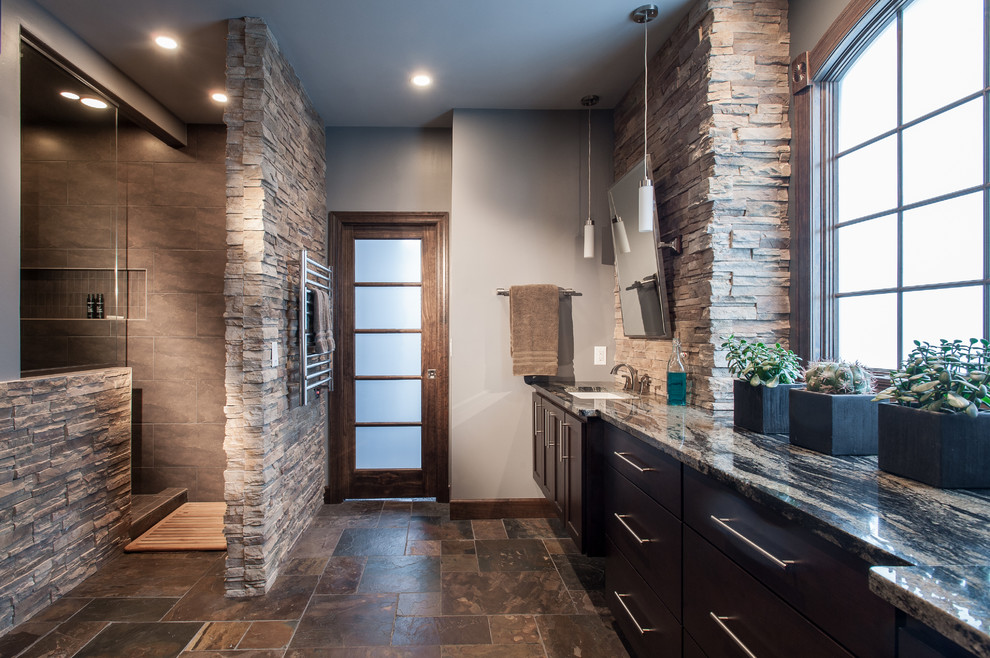 Inredning av ett klassiskt badrum, med ett undermonterad handfat, skåp i mörkt trä, en öppen dusch, grå kakel, grå väggar, släta luckor, med dusch som är öppen och brunt golv