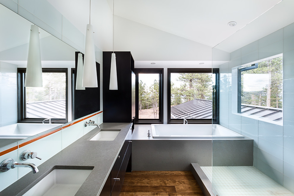 Inspiration for a large contemporary ensuite bathroom in Denver with flat-panel cabinets, dark wood cabinets, a built-in bath, a walk-in shower, a two-piece toilet, blue tiles, glass tiles, white walls, medium hardwood flooring, a submerged sink, concrete worktops, brown floors and an open shower.