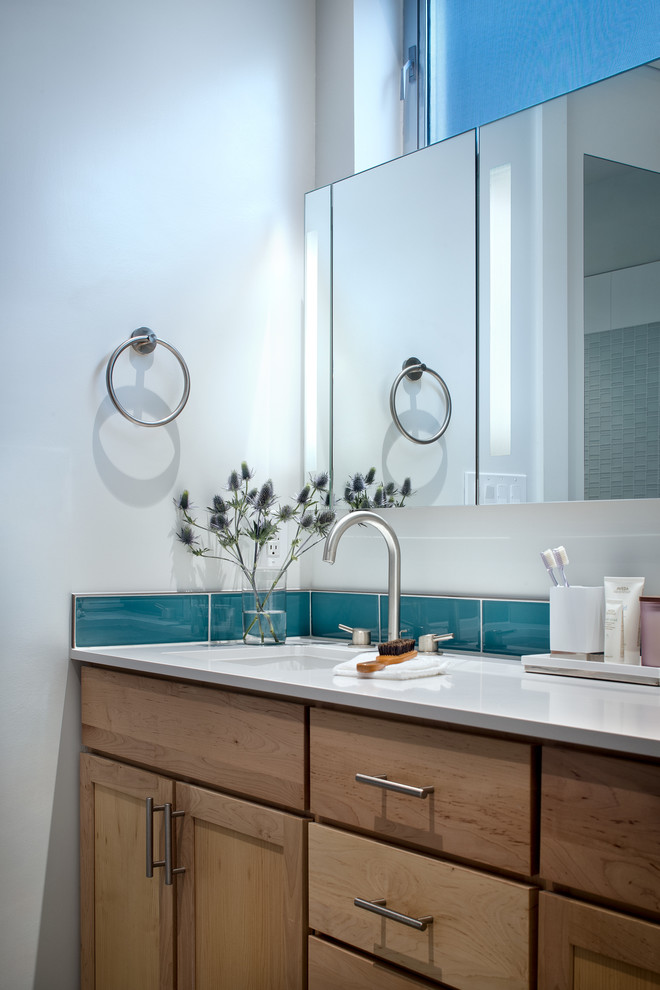 オースティンにある高級な中くらいなコンテンポラリースタイルのおしゃれなマスターバスルーム (シェーカースタイル扉のキャビネット、中間色木目調キャビネット、置き型浴槽、オープン型シャワー、青いタイル、ガラスタイル、白い壁、セラミックタイルの床、アンダーカウンター洗面器、クオーツストーンの洗面台) の写真