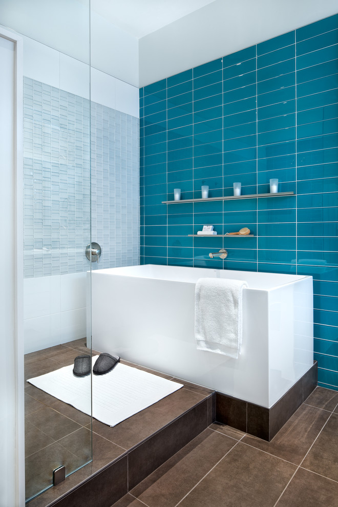 Modelo de cuarto de baño principal actual de tamaño medio con bañera exenta, ducha abierta, baldosas y/o azulejos azules, baldosas y/o azulejos de vidrio, paredes azules y suelo de baldosas de cerámica